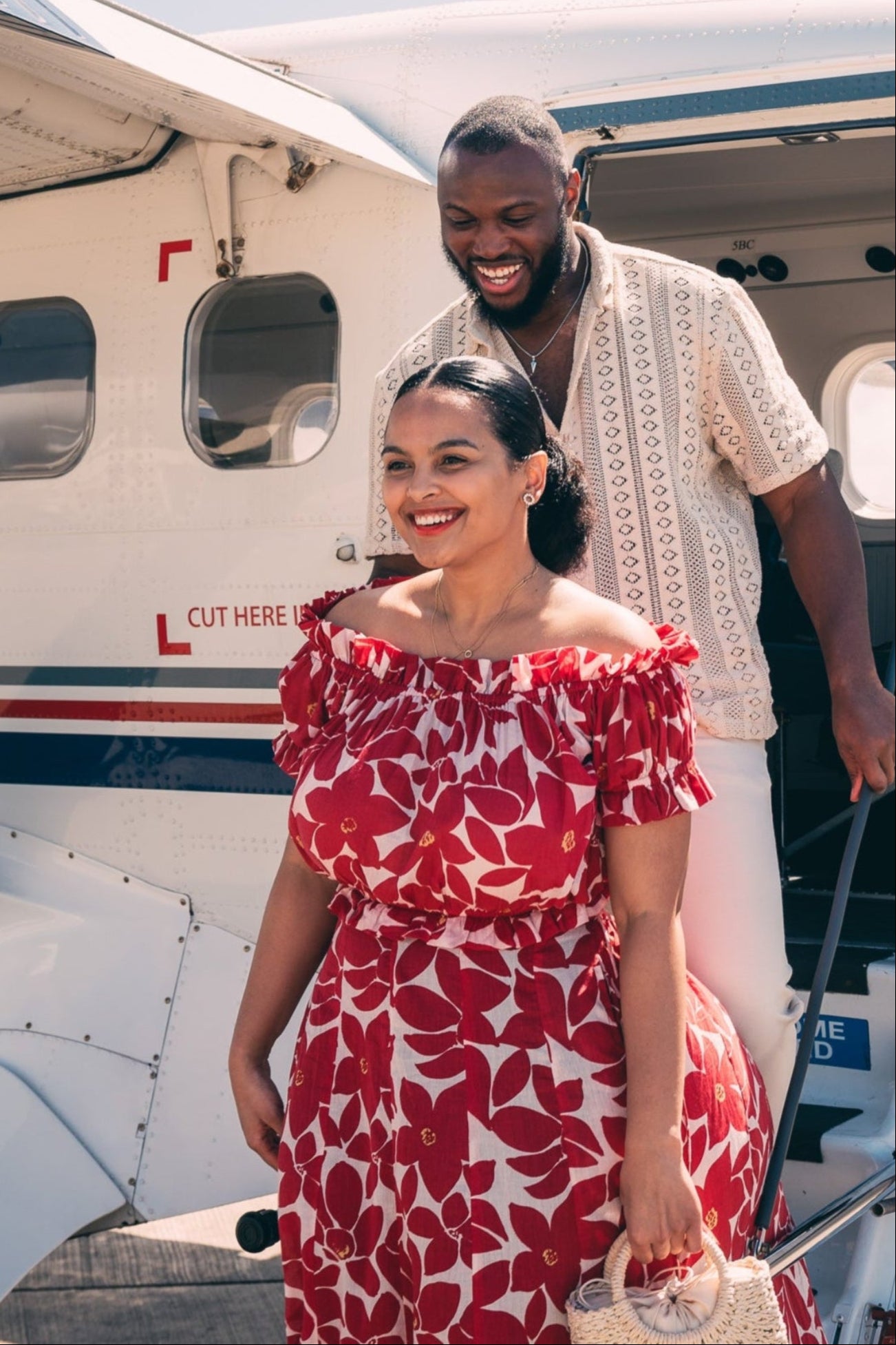 Man and woman walking out of a small airplane on a sunny day.