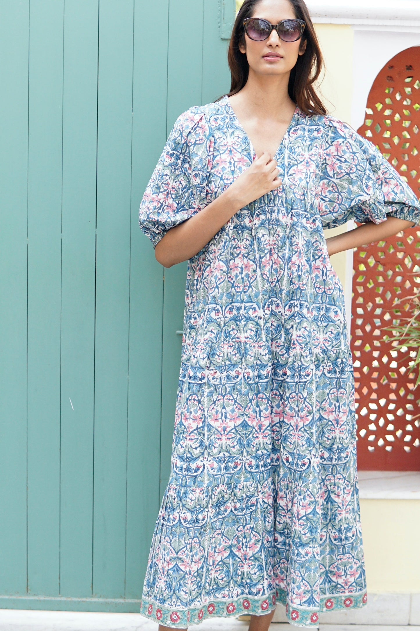 Woman wearing a floral dress with sunglasses outdoors.