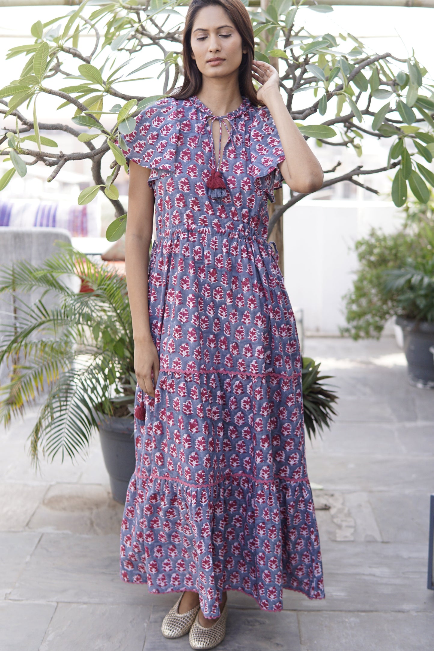 Woman in a floral dress standing outdoors with plants in the background