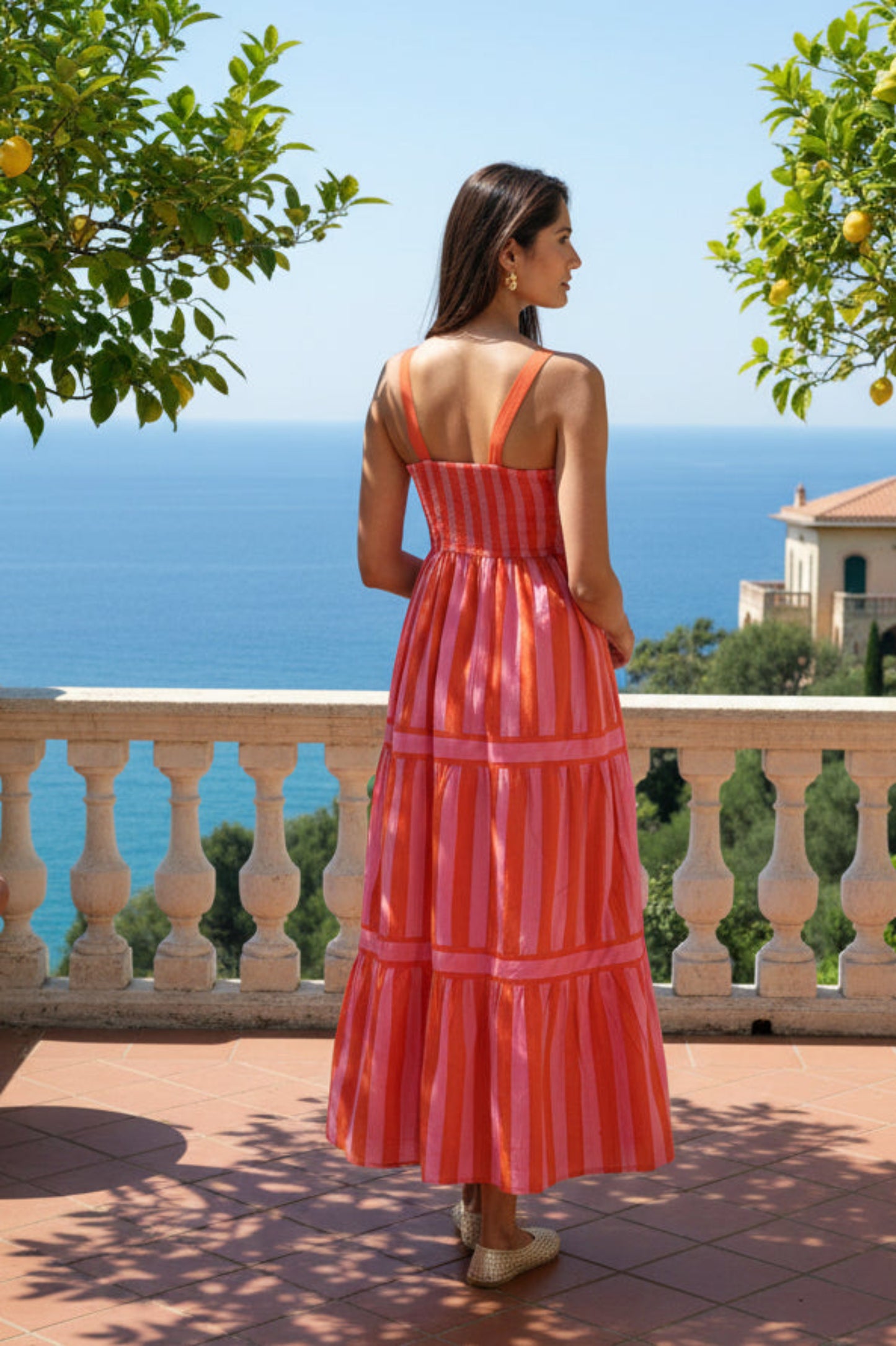 Woman wearing a red and pink striped dress against a white background